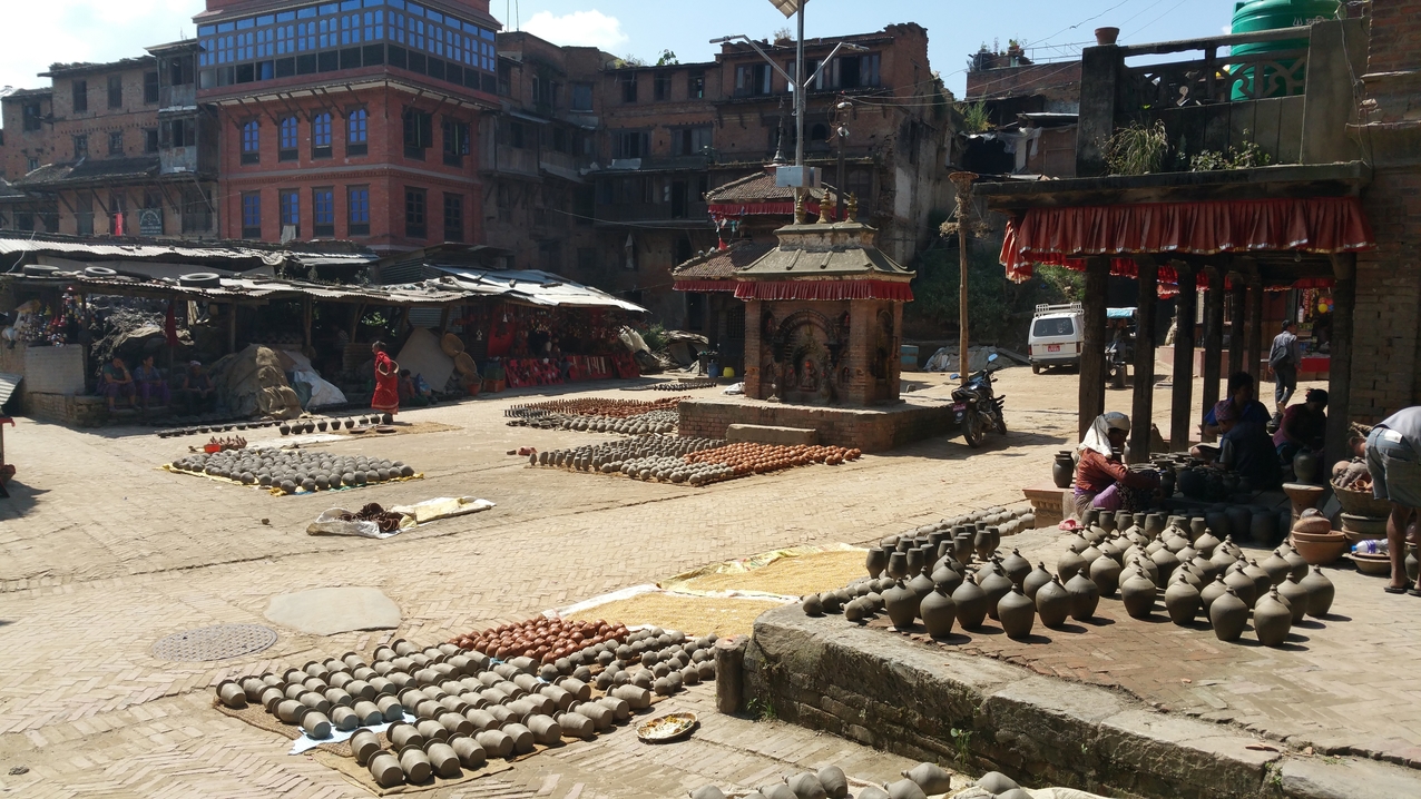 Der Töpfermarkt von Bhaktapur mit dem Ganesh Schrein in der Mitte. Neben der Töpferware wird auch die Reisernte zum trocknen ausgelegt.
